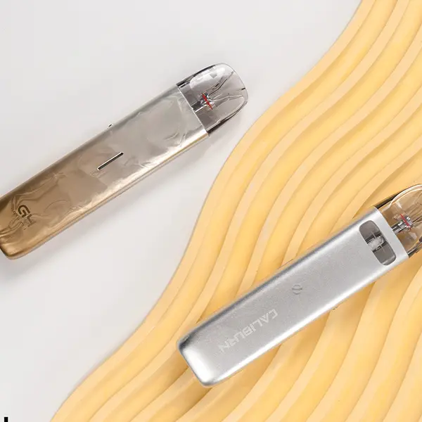 uwell-caliburn-g4-mini-kit-23.jpg Uwell Caliburn G4 Mini Pod Kit in zwei Metallic-Varianten – Bronze-Gold und Silber, liegend auf hellem Untergrund