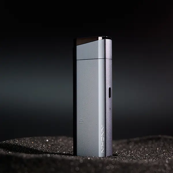 Innokin Klypse Plus Pod Kit in Grau, Lifestyle-Foto auf dunklem Hintergrund mit Sand