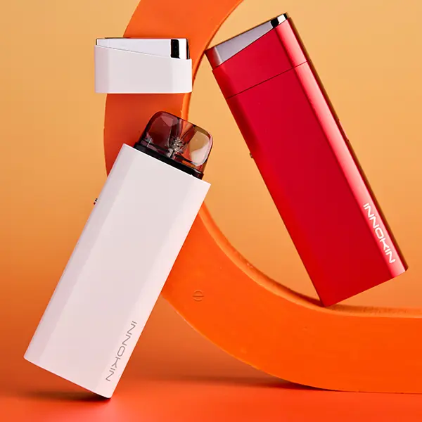 Innokin Klypse Plus Pod Kit in Weiß und Rot auf orangem Hintergrund, zwei Geräte im Vergleich