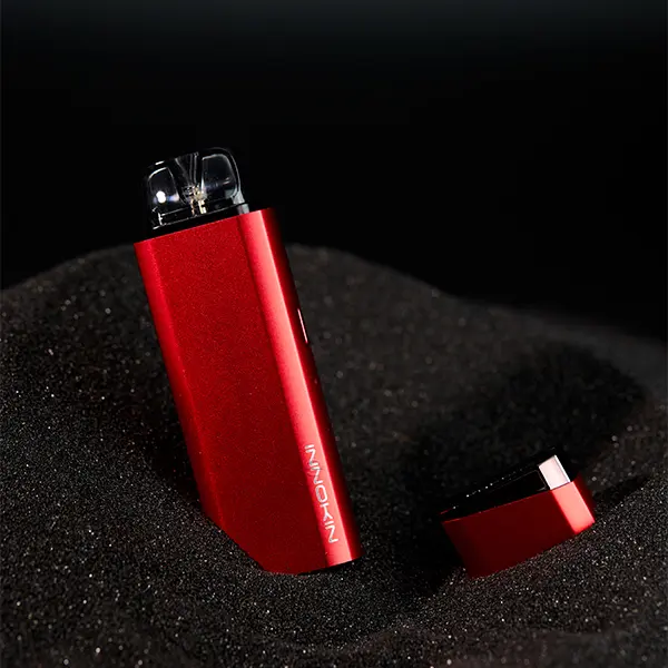 Innokin Klypse Plus Pod Kit in Rot mit eingesetztem Pod auf schwarzem Sandhintergrund