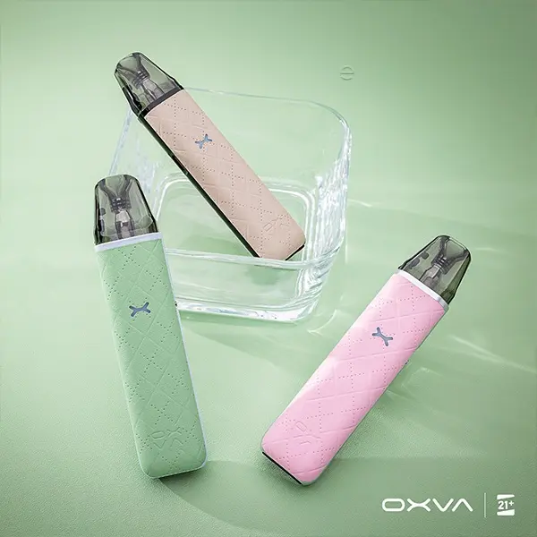 Oxva Xlim Go Pod Kit in Mintgrün, Rosa und Weiß – drei Geräte auf grünem Hintergrund mit Glasscheibe